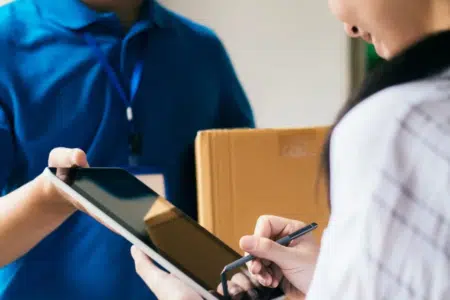 kobieta podpisuje odbiór przesyłki w swoim nowym domu