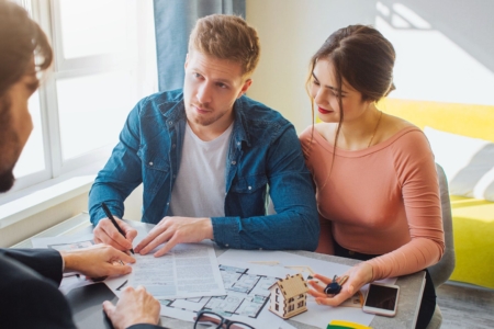 młoda para siedzi przy stole z doradcą kredytowym i rozmawiają o rodzinnym kredycie mieszkaniowym