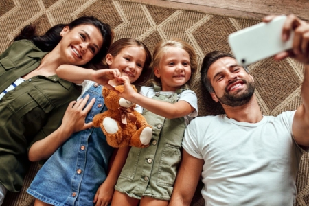 szczęśliwa rodzina z dziećmi leży na dywanie i robią sobie wspólne selfie