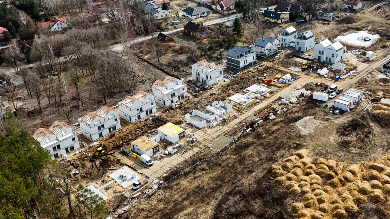 widok z lotu ptaka na osiedle deweloperskie w trakcie budowy na działce pod miastem zachęcające do sprzedaży gruntu deweloperowi