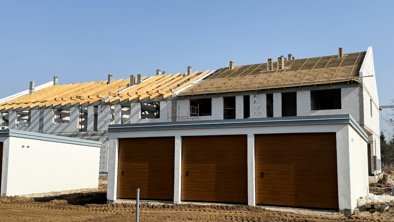 domy z garażami w trakcie budowy pokrywanie dachów blachą w trakcie