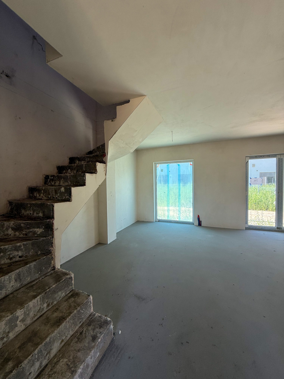 wnętrze budynku salon z oknami panoramicznymi i schodami na górę oraz wyjście do ogrodu