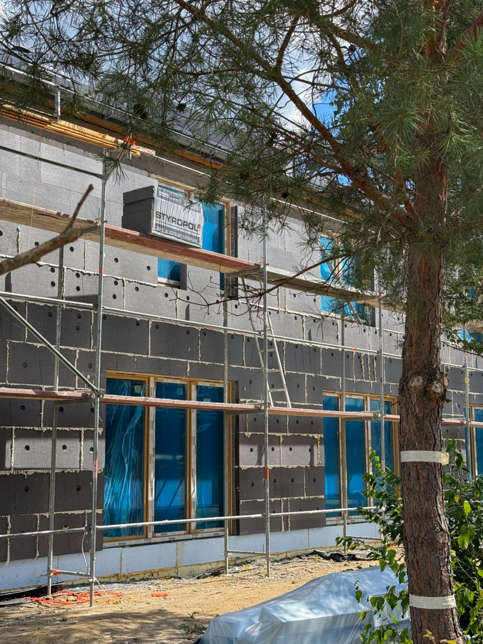 prace na budowie osiedla w Boryszewie prace elewacyjne w trakcie i rusztowania stojące obok budynku