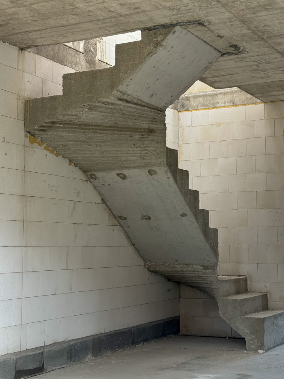 betonowe schody w budynku jednorodzinnym w trakcie budowy schody w rogu salonu łączące parter i piętro