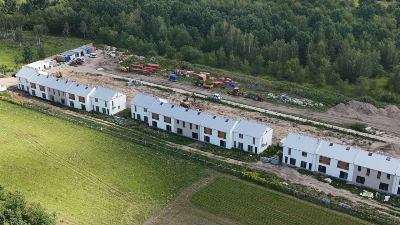 widok z lotu ptaka na osiedle w trakcie budowy i plac budowy oraz okoliczny las