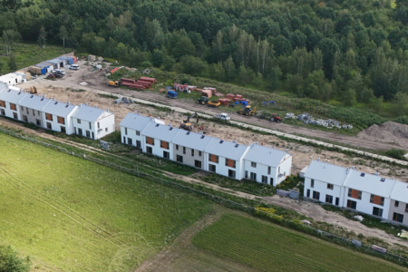 widok z lotu ptaka na osiedle w trakcie budowy i plac budowy oraz okoliczny las